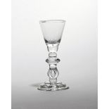 A rare baluster wine glass c.1725, with rounded funnel bowl raised on a baluster stem with half knop