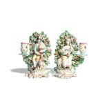 A pair of Derby figures of musical shepherds c.1760, each modelled seated before flowering bocage,