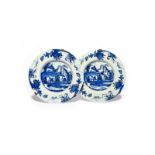 A pair of Delft plates 18th/19th century, painted in blue with low huts beneath fringed trees, the