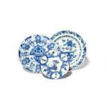 Three Delft plates or chargers 18th century, one painted with a central vase of flowers and