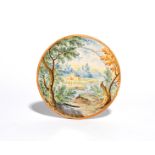A small Castelli maiolica plate mid 18th century, painted in a typical muted palette with distant
