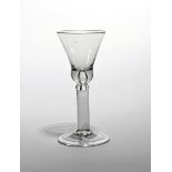 A wine glass c.1740, the base of the bell bowl enclosing a large tear, raised on a thick plain