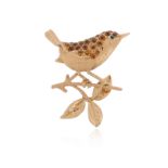 A gold bird brooch, the stylised bird set with citrines and an emerald eye, set on a branch in