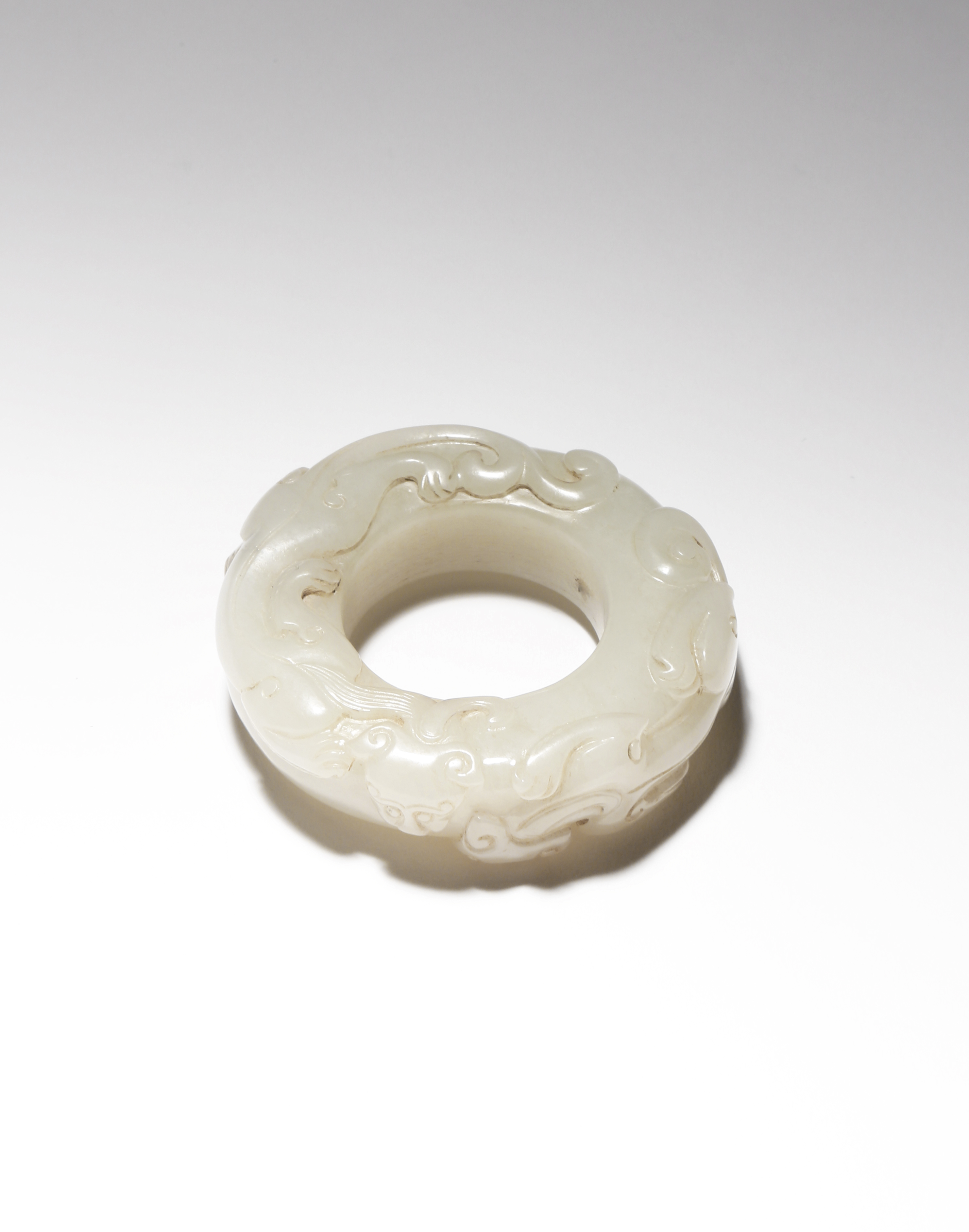 A CHINESE PALE CELADON JADE 'CHILONG' HUAN QING DYNASTY OR LATER Formed as a disc, carved in