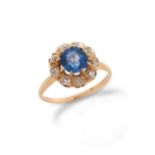 A sapphire and diamond cluster ring, the circular-cut sapphire is set within a surround of old