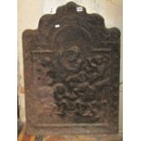 An antique cast iron fire back of stepped arched form with raised relief detail, 58cm wide x 82cm