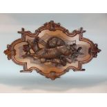 Black Forest carved walnut plaque of serpentine form, decorated with a leaping mountain goat over