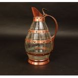 A cut glass claret jug, overlaid with copper bands, looped handle and cover
