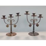 Pair of arts and crafts ebonised wrought iron twin branch candelabra, both with suspended twin heart