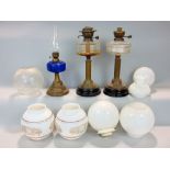 A collection of oil lamps to include two corinthian column lamps and a further lamp with blue