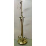 A polished brass floorstanding telescopic oil lamp standard, the central stem surrounded by scrolled