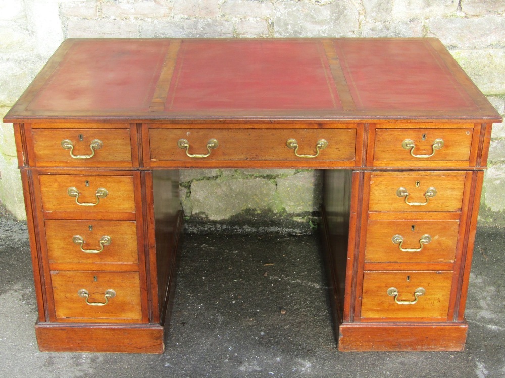 An Edwardian walnut kneehole twin pedestal writing desk, with triple leather inset panel top, over