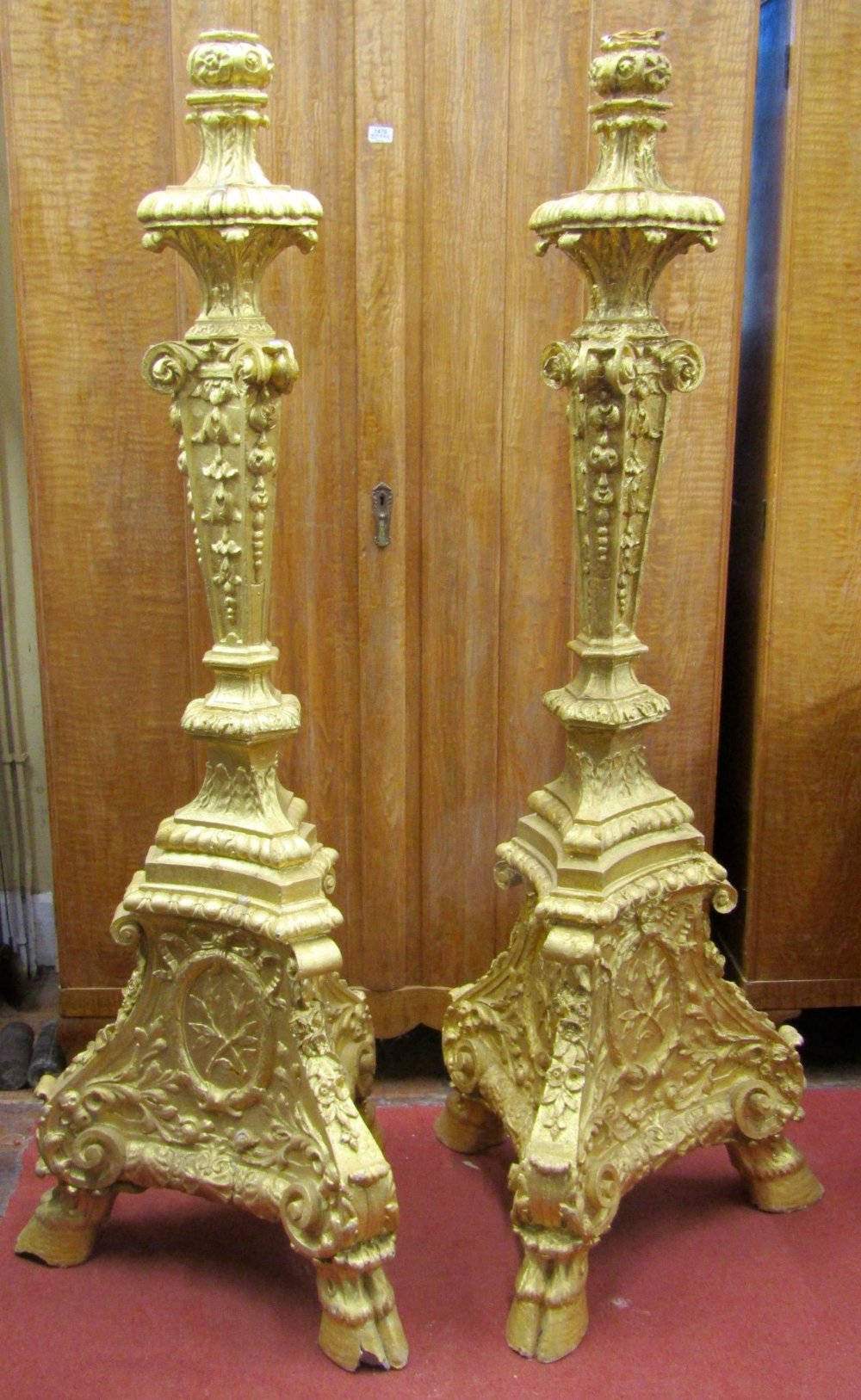 A pair of substantial cast torcheres or lamp standards on tricorn bases, with hoof supports and