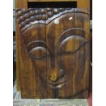 A hardwood boarded wall plaque with carved Buddhistic face mask detail, 77cm x 60cm approx.