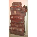 A collection (stack of) seven vintage brown fibre and leather re-enforced suitcases of varying