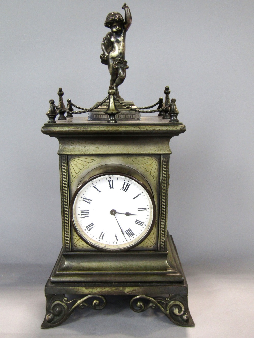 French brass cased figural mantle clock mounted by a cherub with gallery rail, twin cherub type