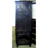 A 19th century oak corner cupboard enclosed by two pairs of panelled doors with carved detail,