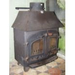 A Villager cast iron wood burning stove, enclosed by a pair of arched and glazed panel doors with