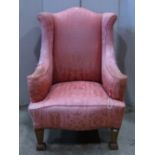 A Georgian style wing armchair, with shaped outline, pink ground upholstery, with classical arch,