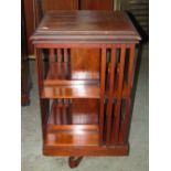 An Edwardian walnut floorstanding revolving bookcase of square cut form, with segmented shelves