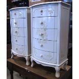 A pair of bow-fronted tall bedside chests of four long drawers with cream painted finish and
