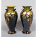 A pair of Phoenix ware two handled vases, with painted and gilded peacock decoration and printed