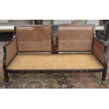 An Edwardian Bergere sofa in an 18th century manner with cane panelled back and sides, within