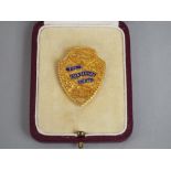 A 9ct gold shield shaped lapel badge with enamelled detail - For Long Service L.B. Ltd - 25 Years, 9