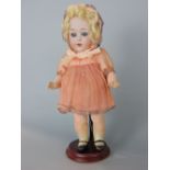 Early 20th century bisque headed German doll probably by Gebruder Heubach, with blonde curly hair,