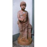 A weathered contemporary terracotta garden statue in the form of a classical standing boy, holding a