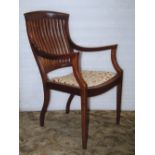 An arts and crafts open elbow chair with curved slender slatted back over an upholstered pad seat,