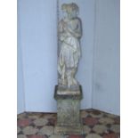A weathered cast composition stone garden statue in the form of a classical female raised on a