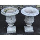 A pair of composition stone campana shaped garden urns, with flared egg and dart rims, raised relief