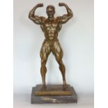Cast bronze figural study of a body builder posing, upon a black marble plinth base, 52cm high