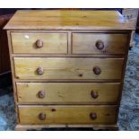 A modern stripped pine bedroom chest in a Georgian style of two short over three long drawers raised