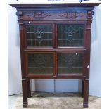 An oak side cabinet with stepped and moulded cornice over two pairs of green stained leaded light