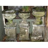 A pair of weathered composition stone garden urns, the squat circular bowls with flared rims and