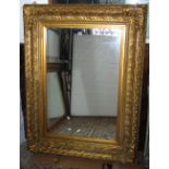 A large reproduction gilt framed wall mirror of rectangular form, the deep moulded frame with