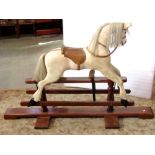 A traditional wooden rocking horse, with painted finish, horse hair tail and mane, soft leather