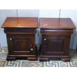 A pair of hardwood bedside cupboards, each enclosed by a fielded panelled door and frieze drawer,