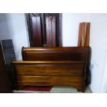 A reproduction hardwood sleigh bed, with scrolled and panelled head and footboards, complete with