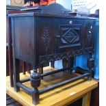 A low Old English style oak side cupboard with applied mouldings and lozenge shaped panels partially