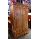 A modern stripped pine wardrobe in the Georgian style with stepped and moulded cornice over a pair