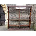 A Victorian oak open bookcase with pegged frame and segmented shelves beneath a carved frieze (