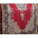Belgian carpet with central blue and pink floral medallion upon a red ground, 310 x 210cm