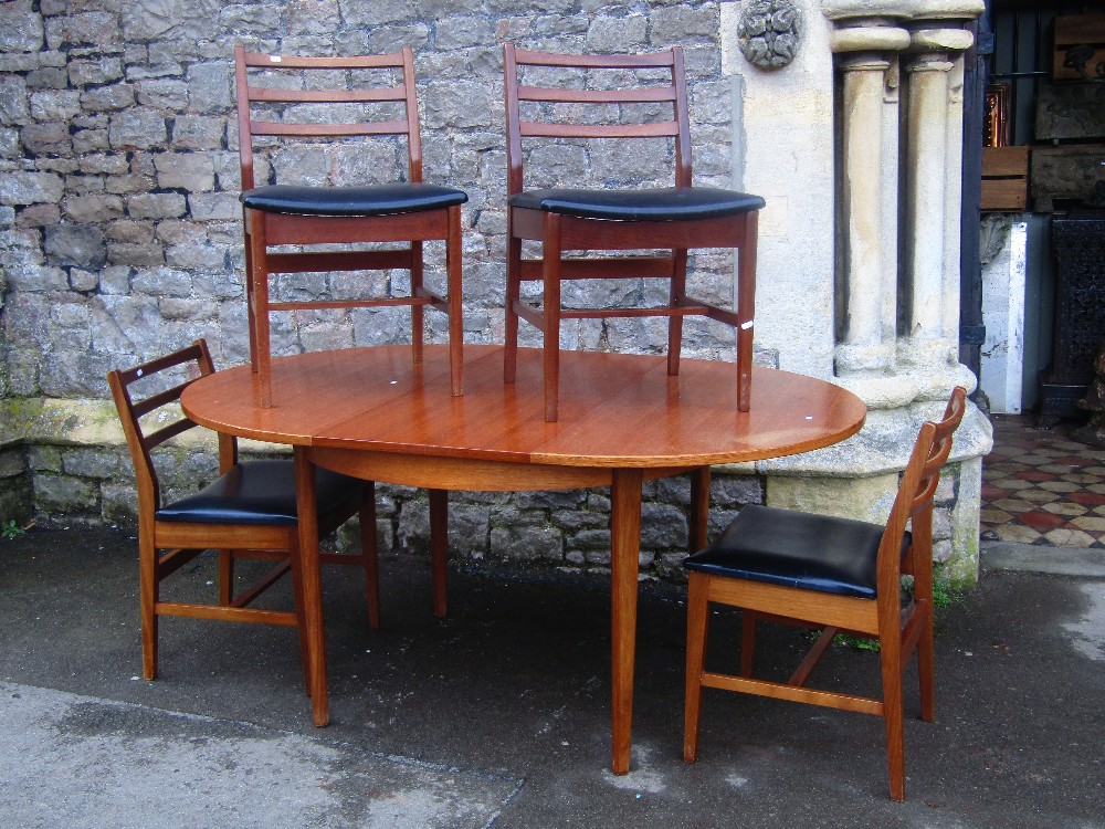 A retro teak D end extending dining table with single additional bi-fold leaf raised on four