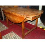 A 19th century stripped pine oval dropleaf kitchen table with end frieze drawer raised on four