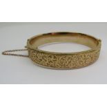 9ct hinged bangle with scrolled decoration, 12.8g