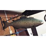 A moulded tin shop display sign in the form of a salmon, hung from a wall mounted bracket, the