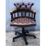 A reproduction swivel captains type office swivel desk chair with buttoned upholstery and five prong